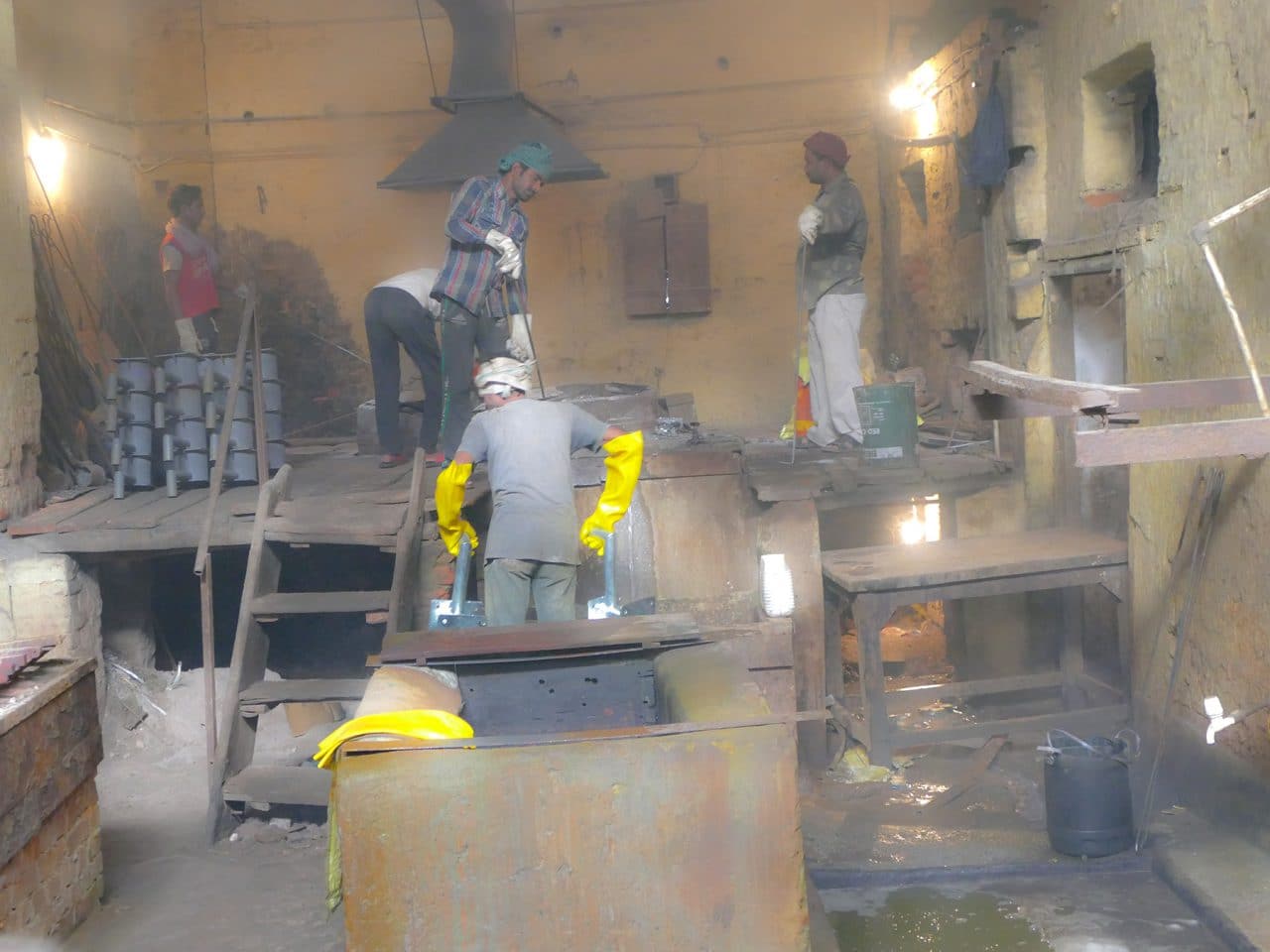 Workers hot-dip galvanizing steel components in a molten zinc bath at the S K Industries factory