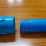 Blue PVC riser pipe with square-cut threads next to its coupling socket