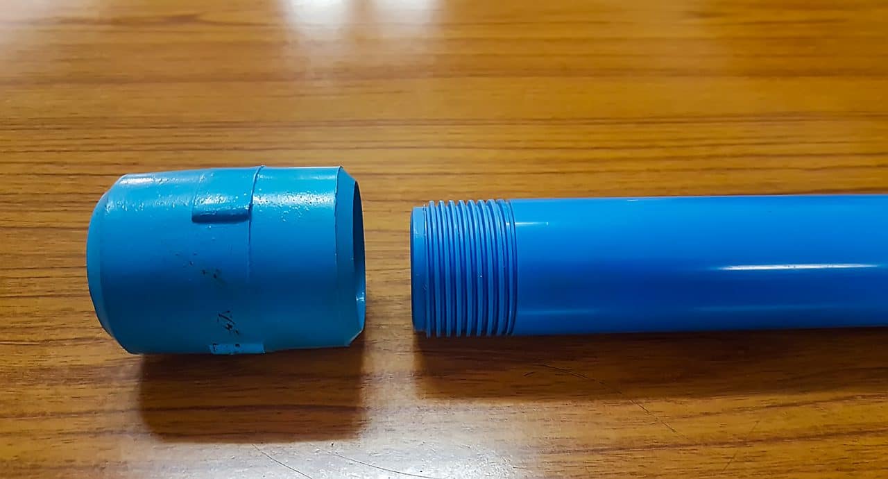 Blue PVC riser pipe with square-cut threads next to its coupling socket