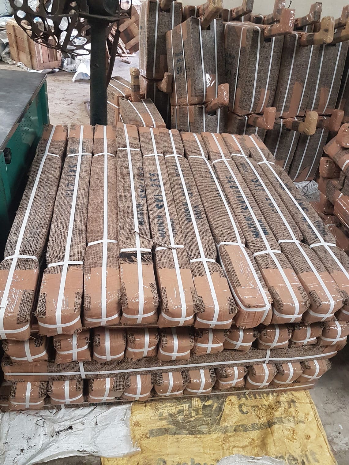 Pallet of hessian-wrapped hand pump parts staged for loading at the SKI warehouse