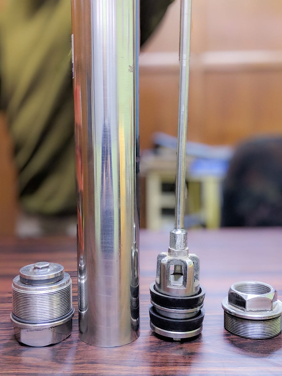 Stainless steel cylinder assembly parts laid out separately - cylinder tube, piston, footvalve and top cap